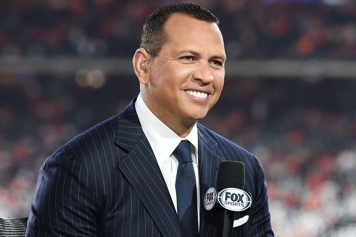 Alex Rodriguez wearing a blue stripes suit while holding a mic
