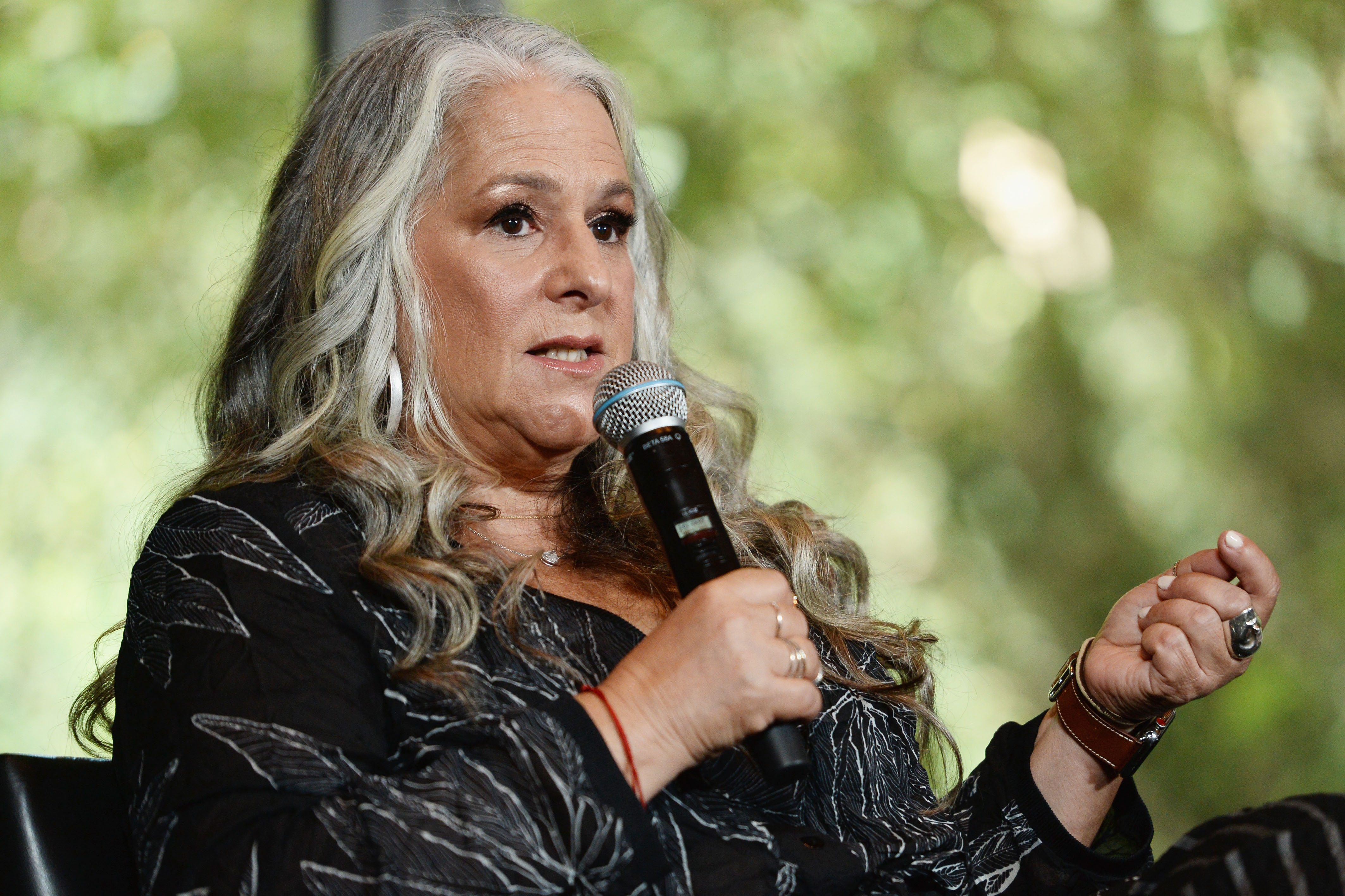 Marta Kauffman wearing a black outfit while holding a mic