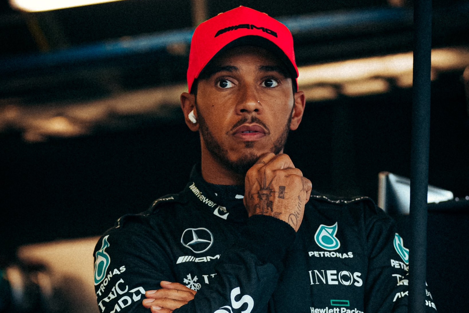 Lewis Hamilton wearing a black jacket and red cap