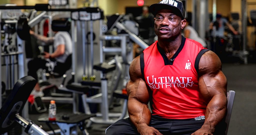 Dexter Jackson wearing white top and black cap in a gym