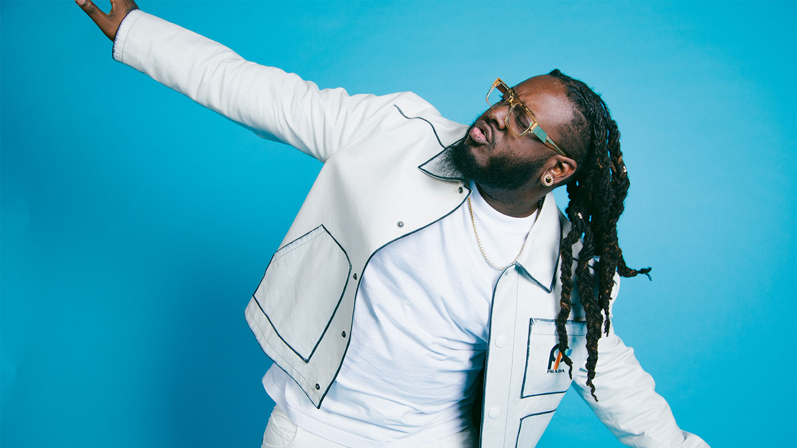 T-Pain wearring a white shirt and white jacket while spreading his arms