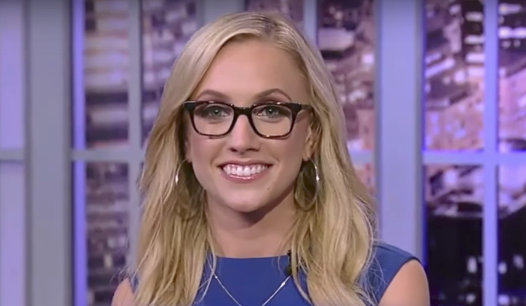 Kat Timpf wearing a blue gown with an eye glass having a huge smile on her face