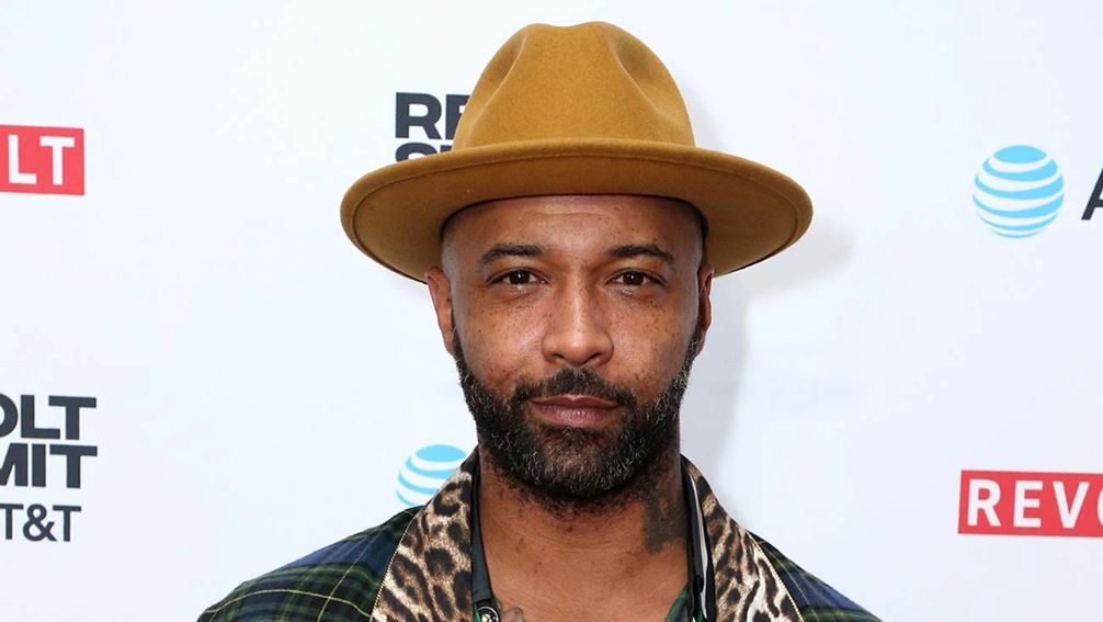 Joe Budden wearing a gold colored hat at an event