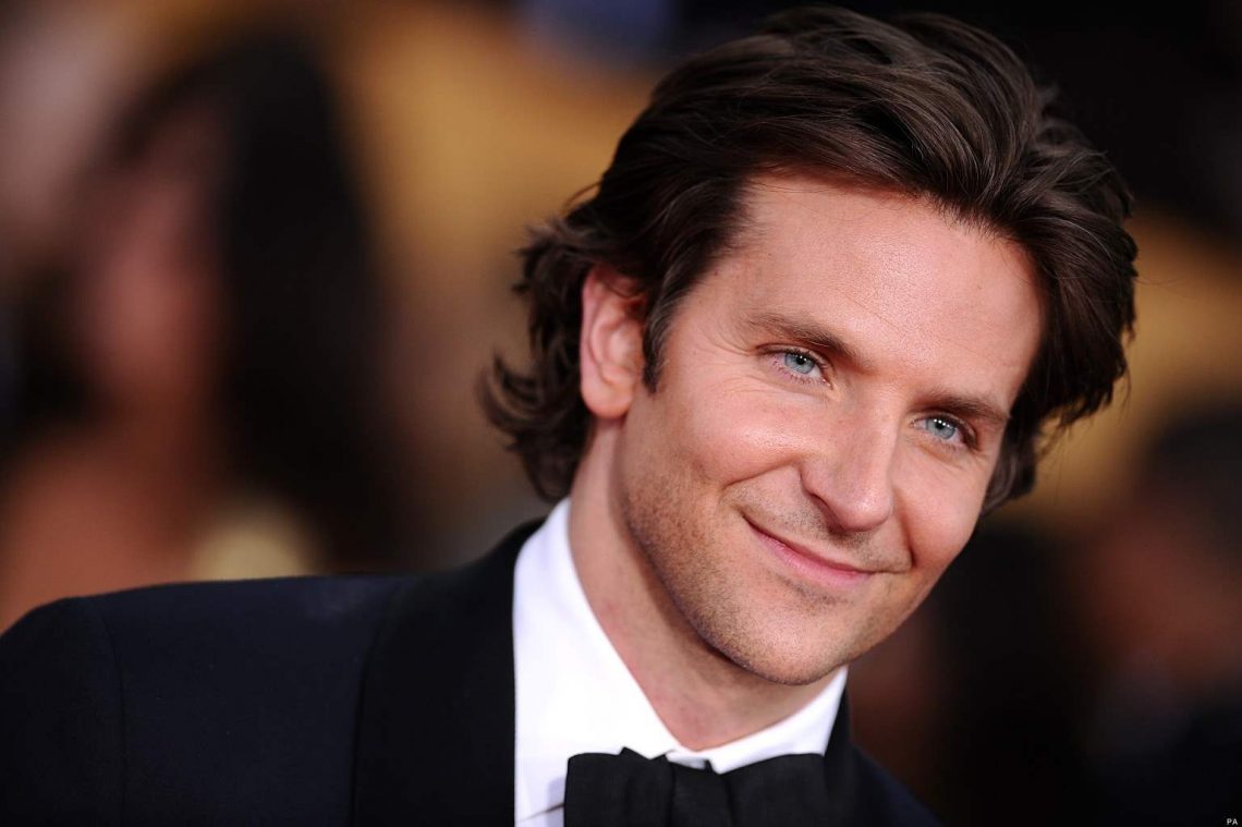 Bradley Cooper wearing a black suit and black bow tie