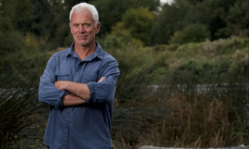 Jeremy Wade standing in the woods with his hands folded