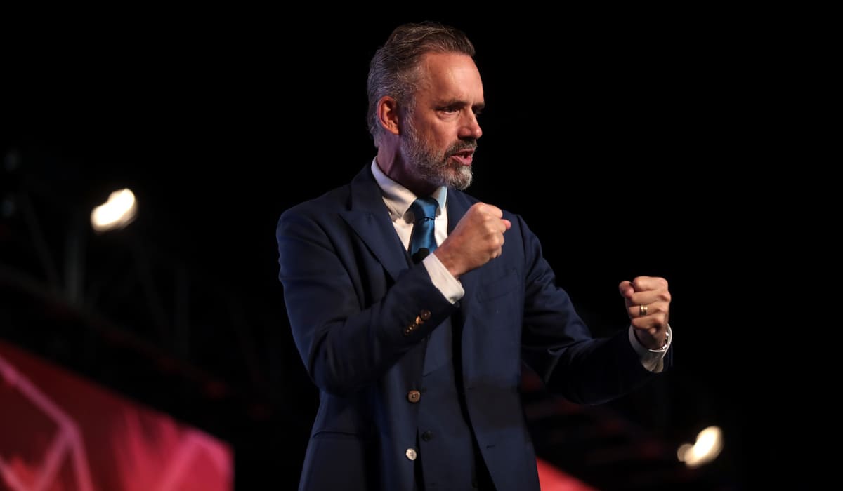 Jordan Peterson standing with clenched fists as he speaks