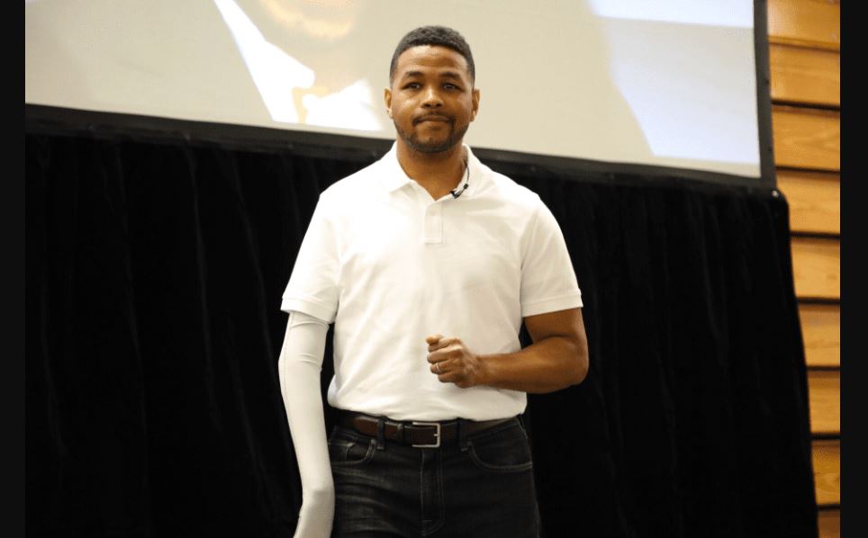 Inky Johnson wearing a white t-shirt and black jeans standing on a podium