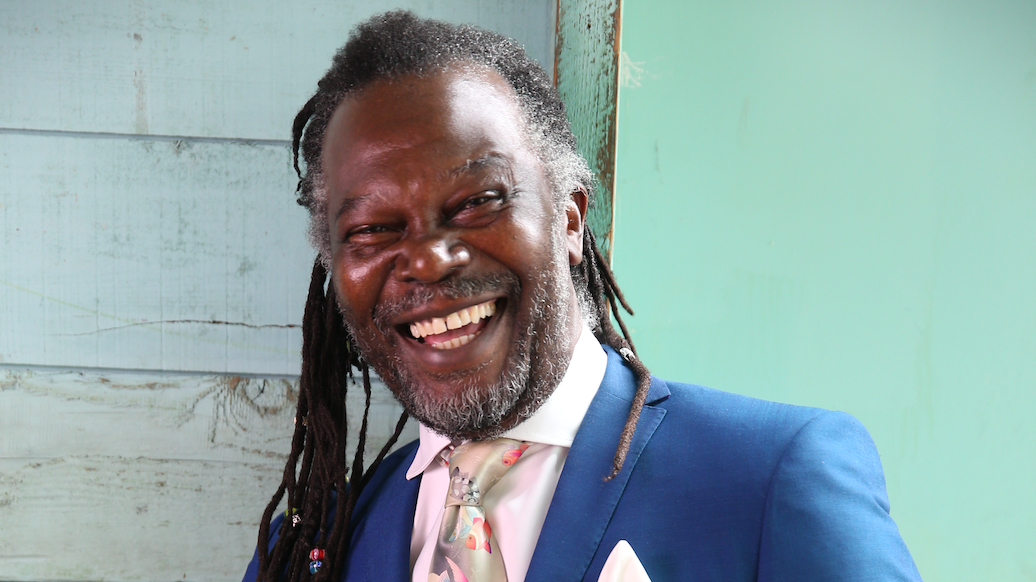 Laughing Levi Roots wearing a blue suit