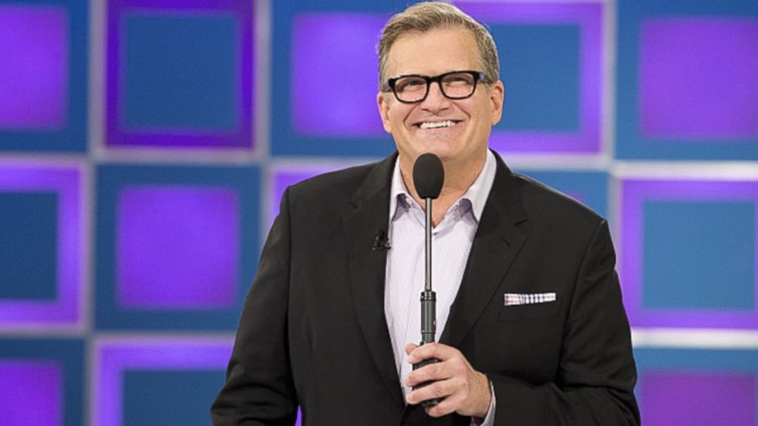 Drew Carey wearing a black coat while holding a mic