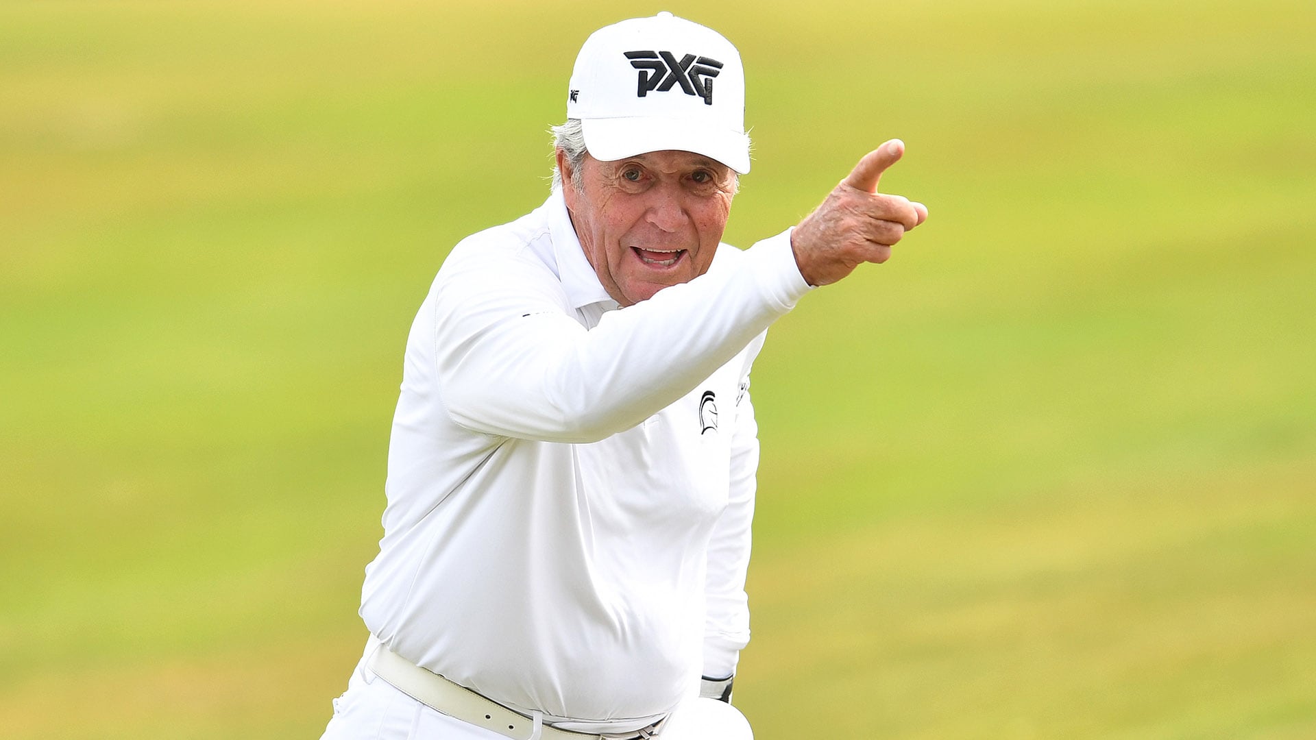 Gary Player wearing a white long sleeves and white cap while raising his arm