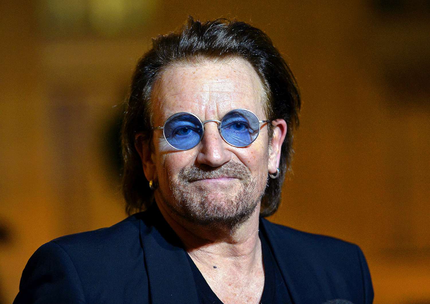 Bono wearing a black suit and eyeglasses