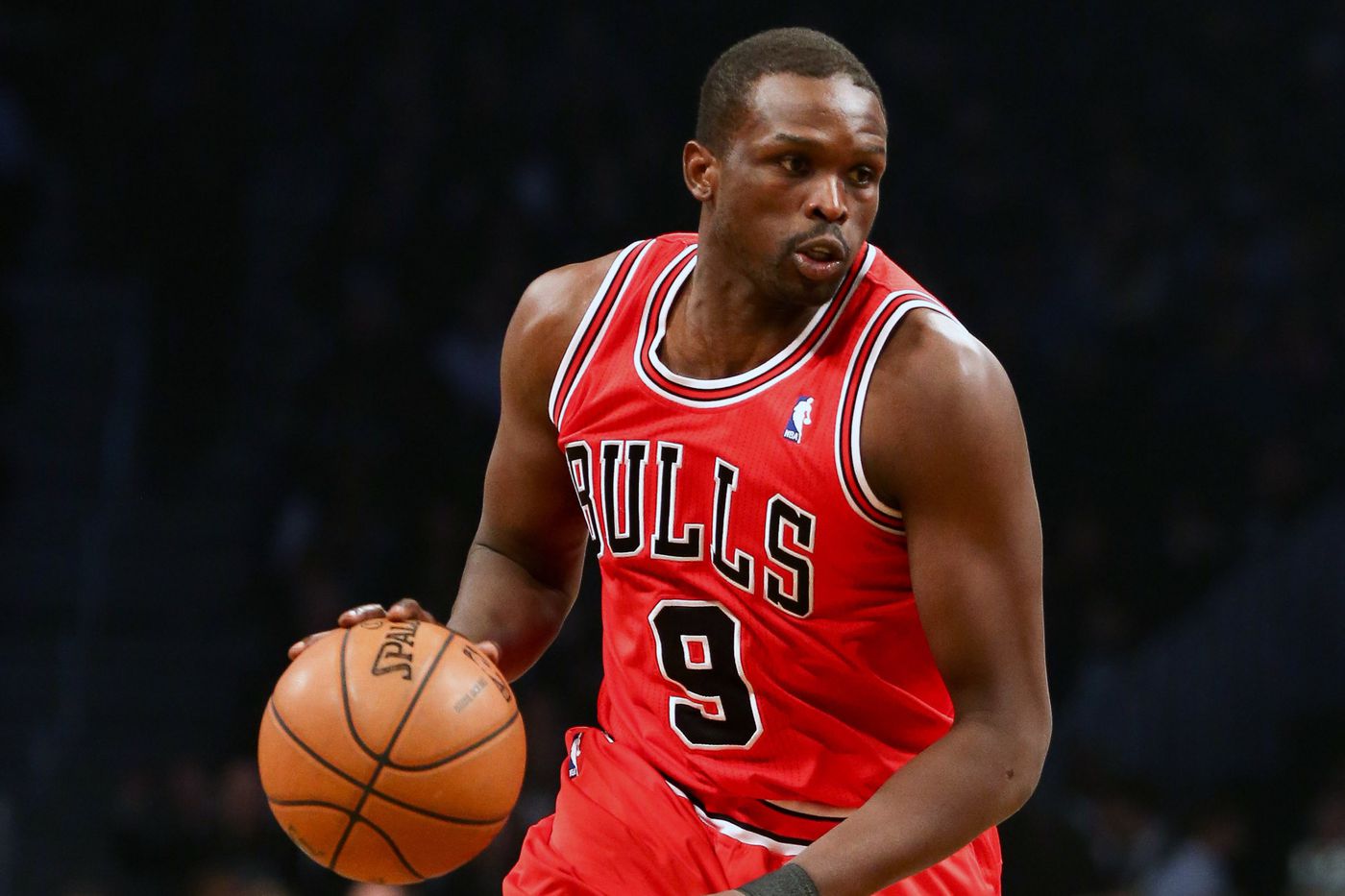 Luol Deng weaaring a red Chicago Bulls basketball jersey while dribbling the ball
