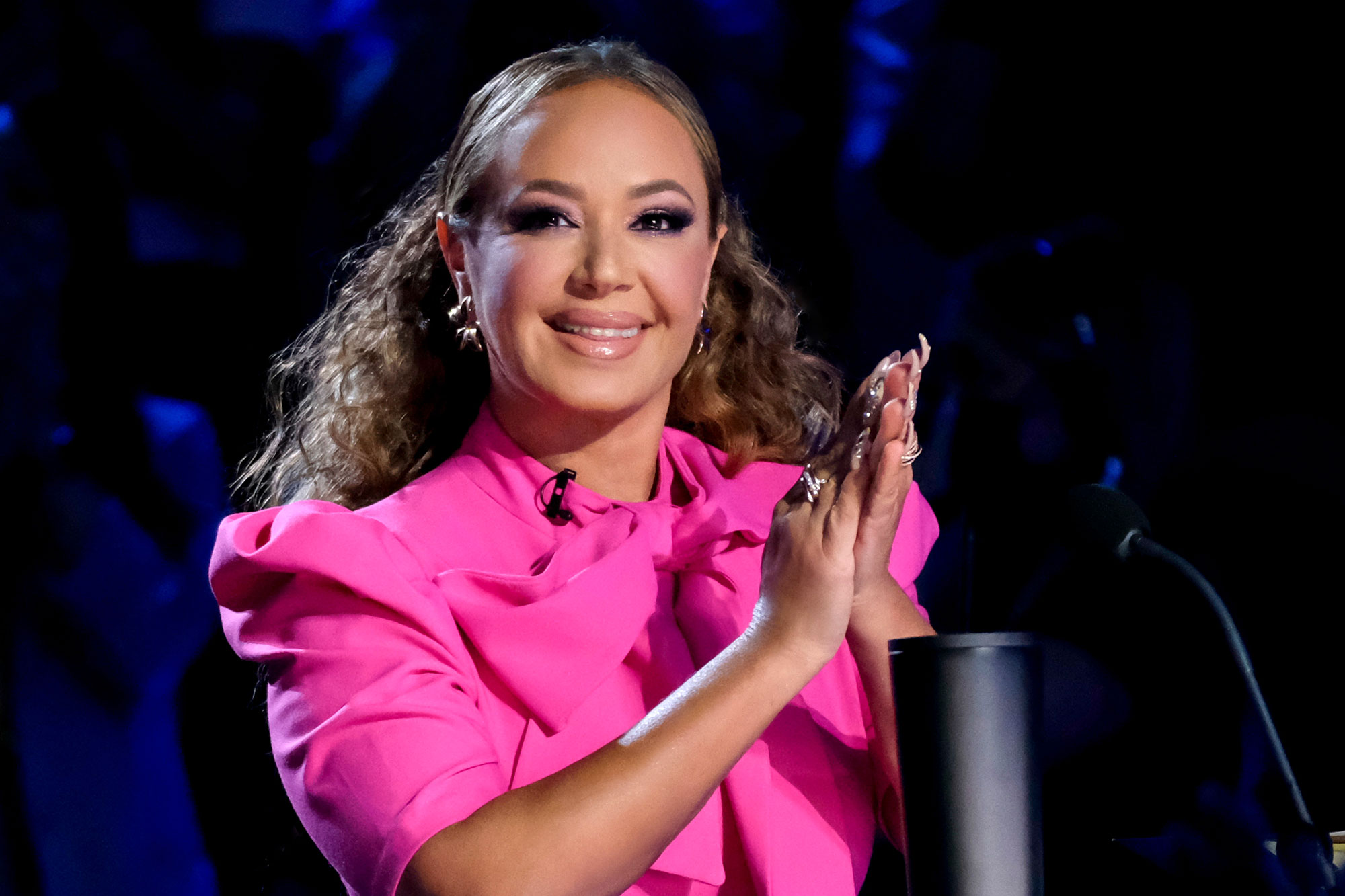 Leah Remini wearing a pink outfit while clapping