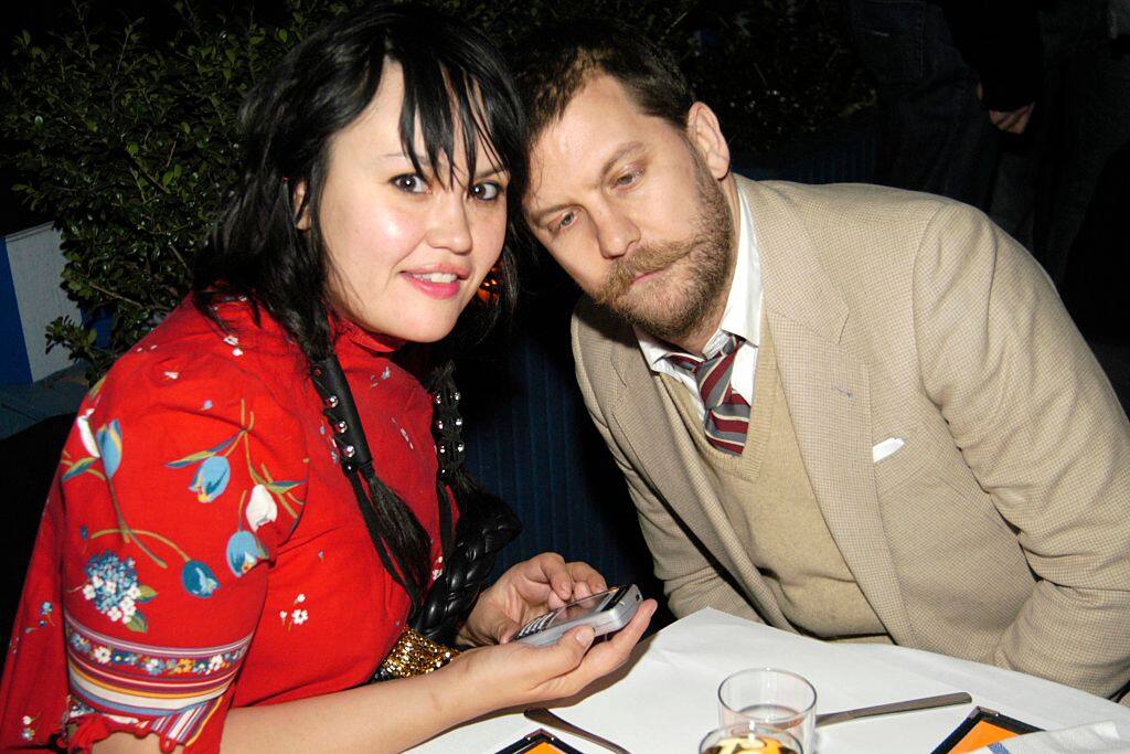 Emily Jendrisak wearing a red outfit with Gavin McInnes wearing a brown suit