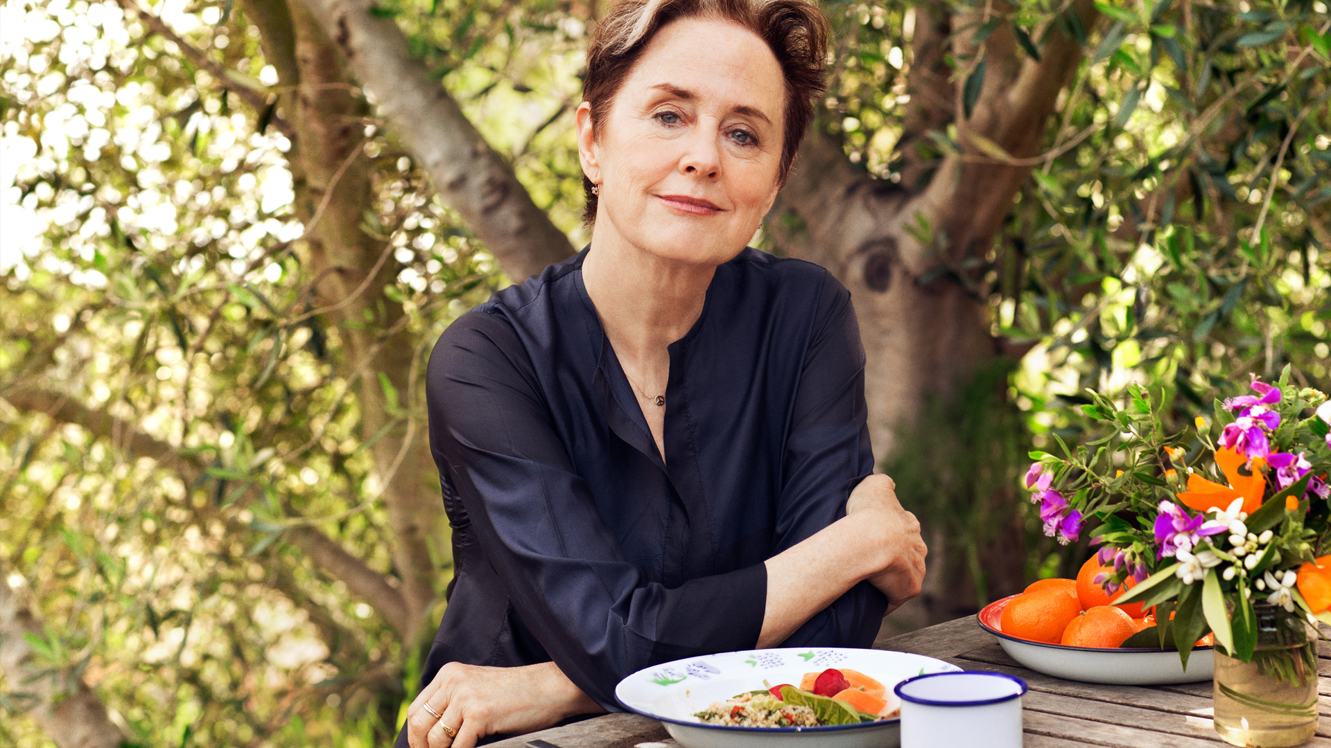 Alice Waters wearing a blue top with food on the table