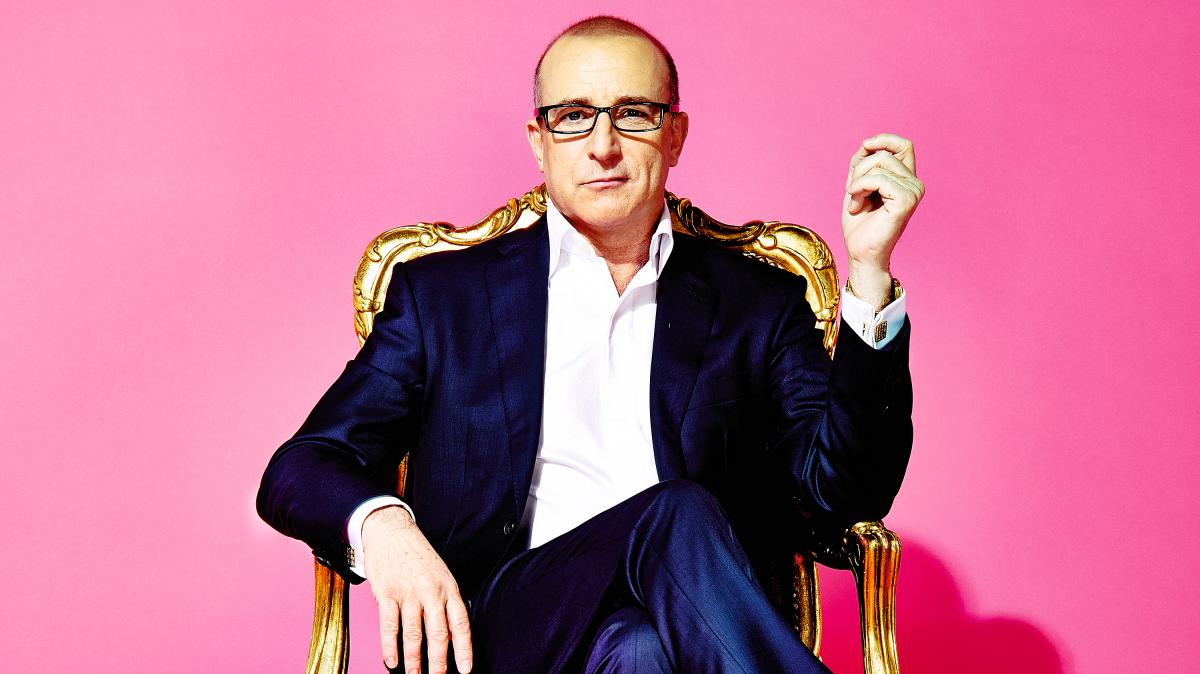Paul McKenna sitting in a gold chair while wearing a blue suit