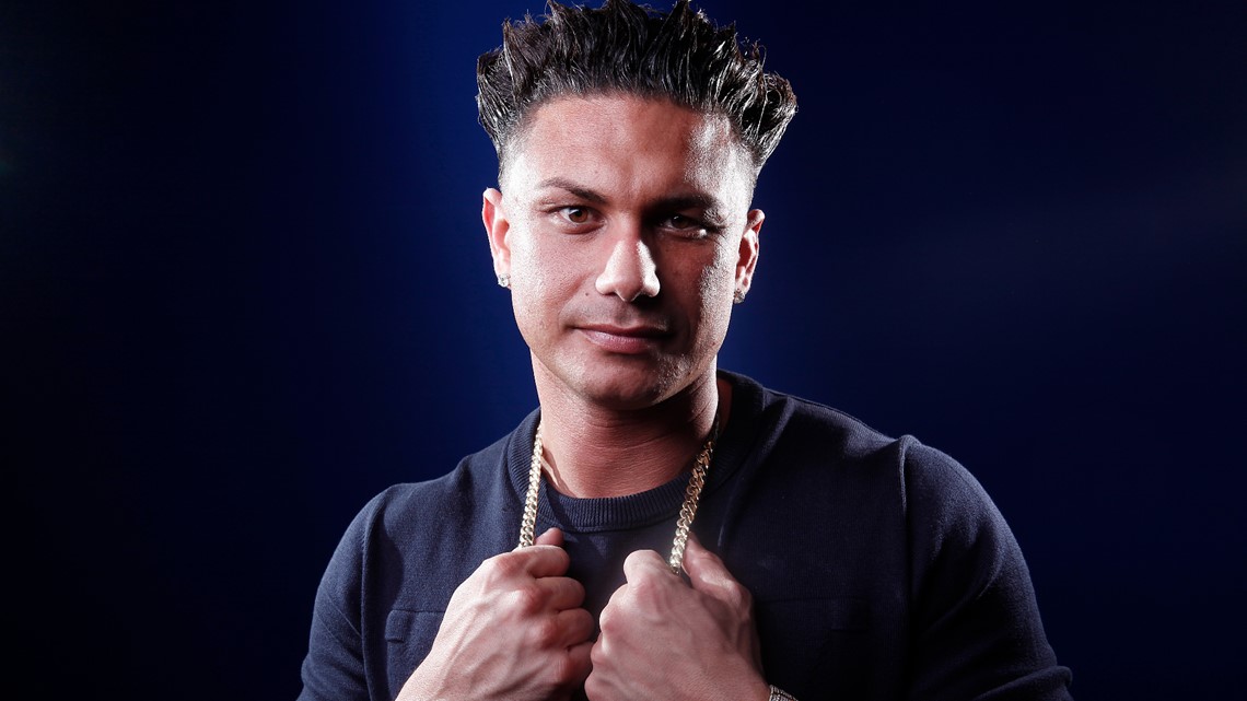 DJ Pauly D wearing a black shirt while holding gold chain on his neck