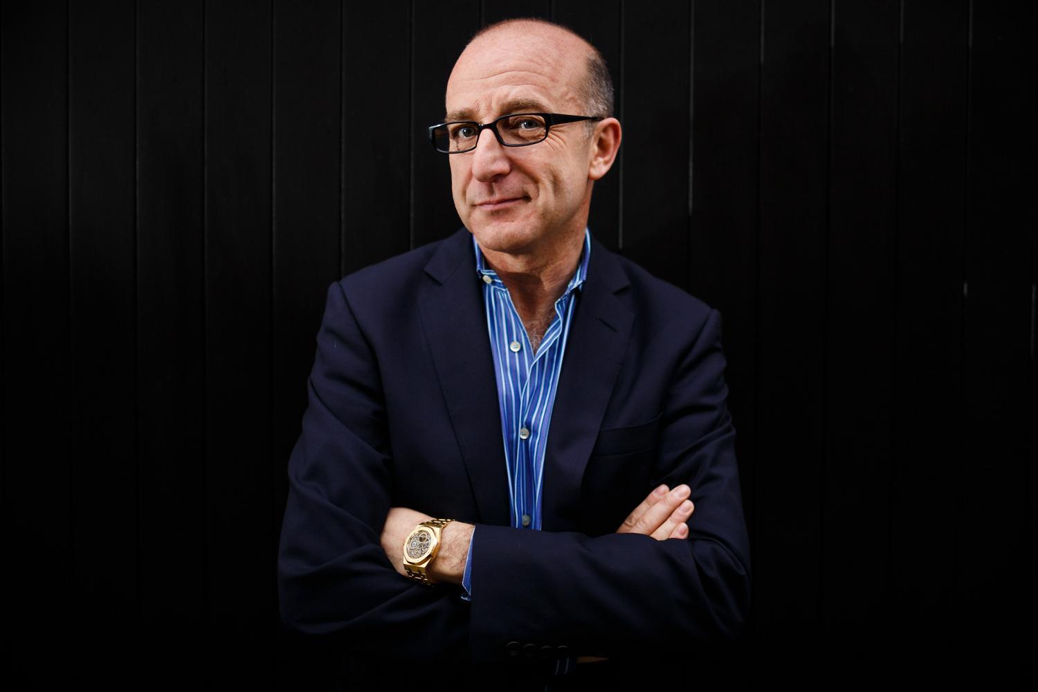 Paul McKenna wearing a black suit and blue polo