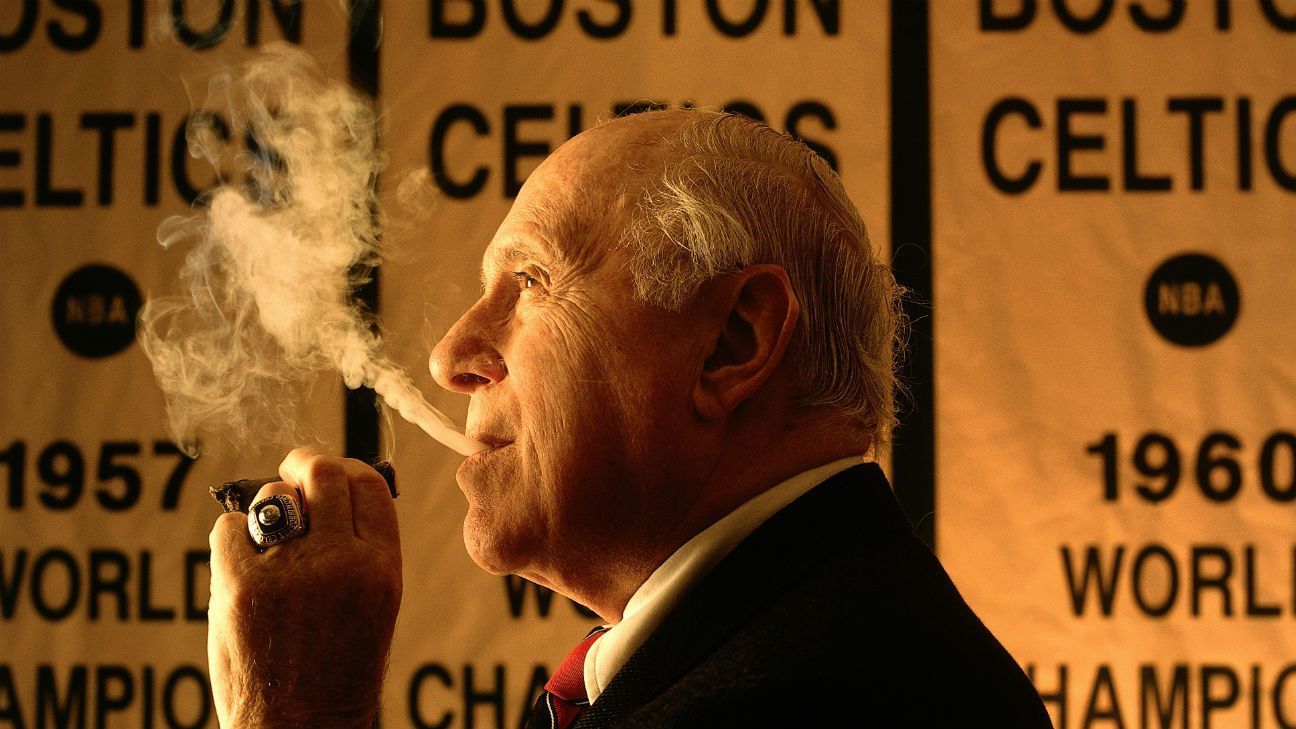 Red Auerbach wearing a black suit while smoking cigar