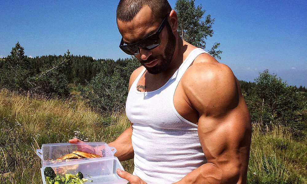 Lazar Angelov wearing a white tank top while holding food 