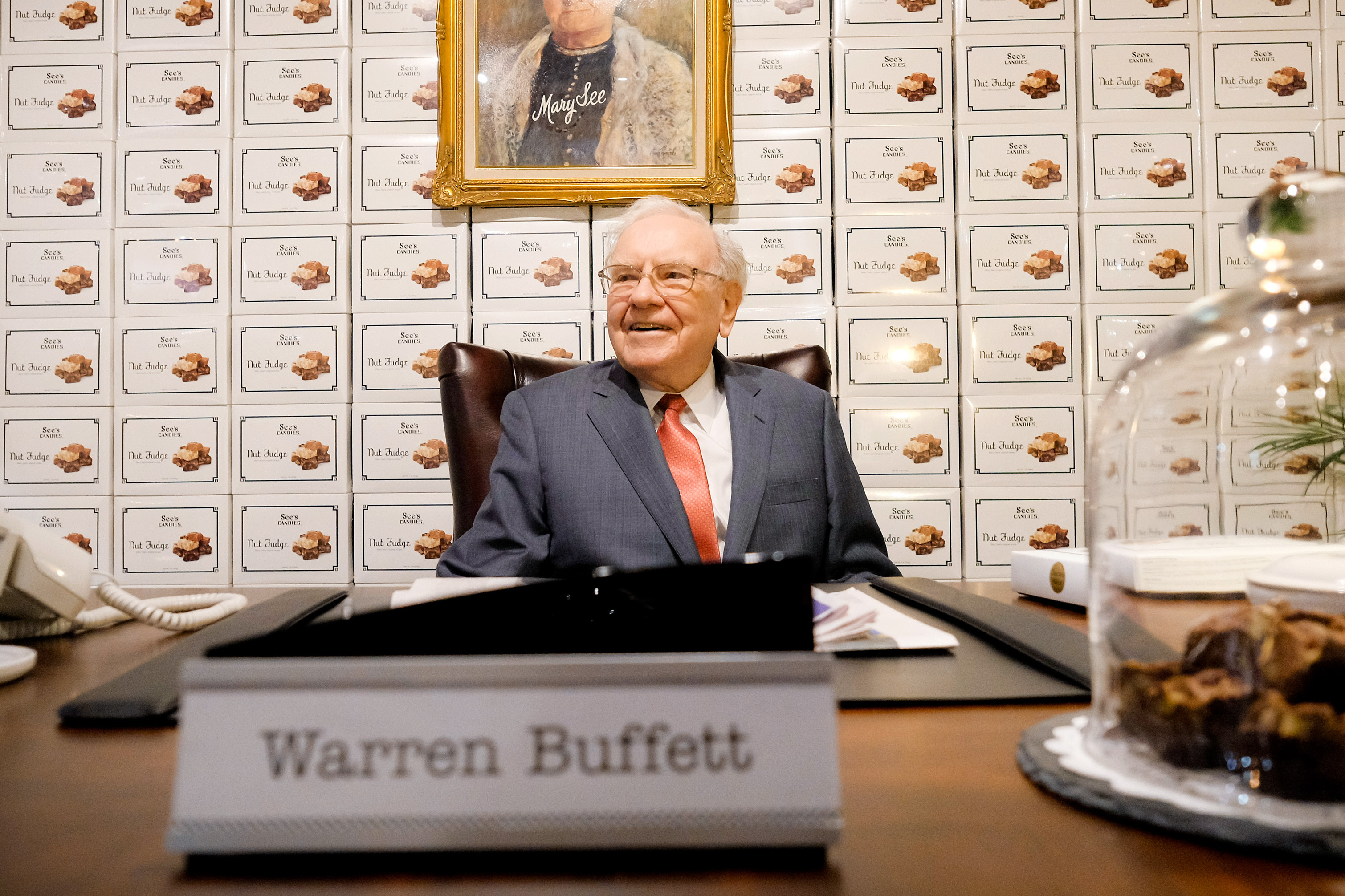 Warren Buffett wearing a blue suit with his name on the table