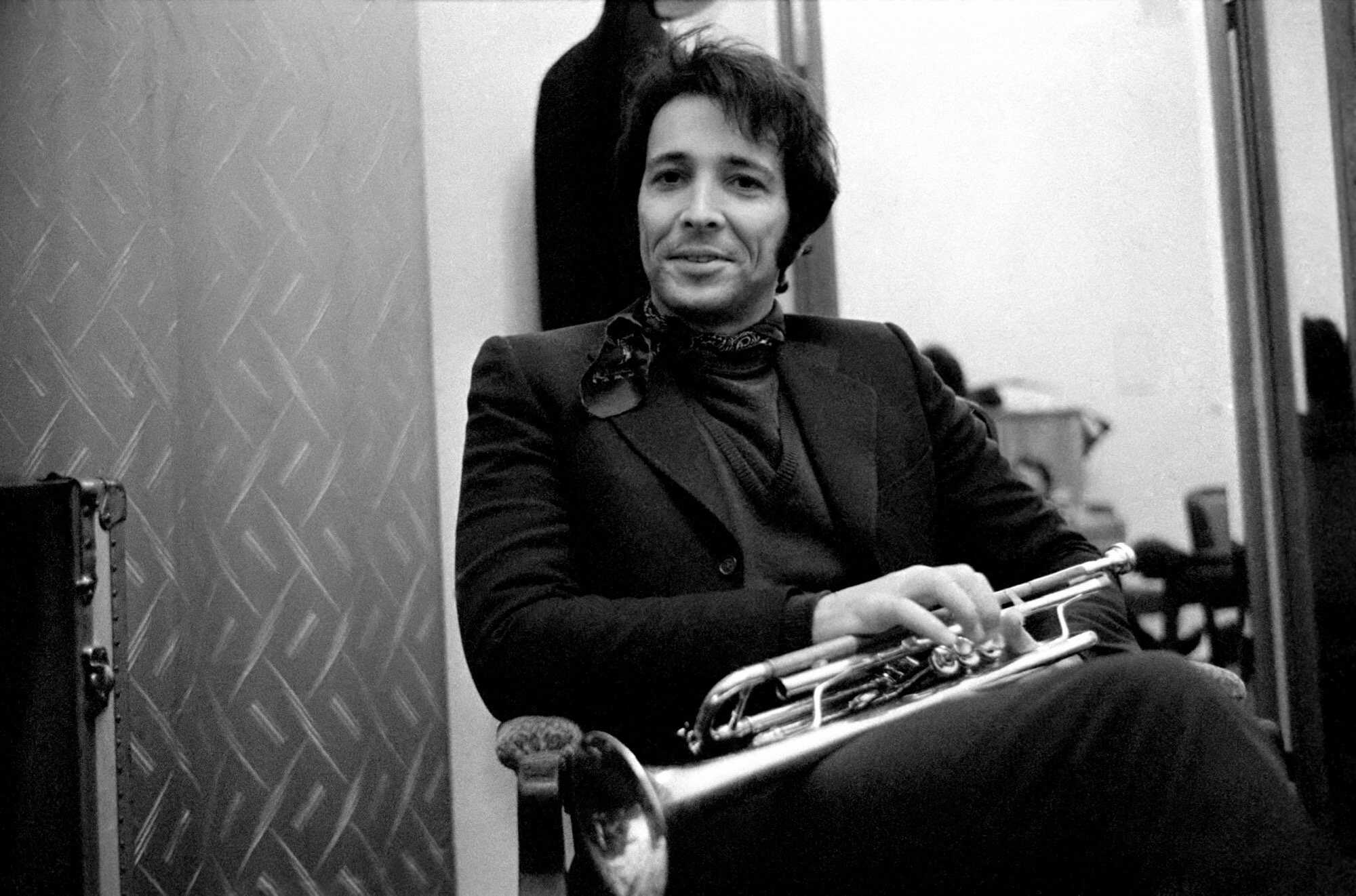 Herb Alpert wearing a suit while holding a trumphet