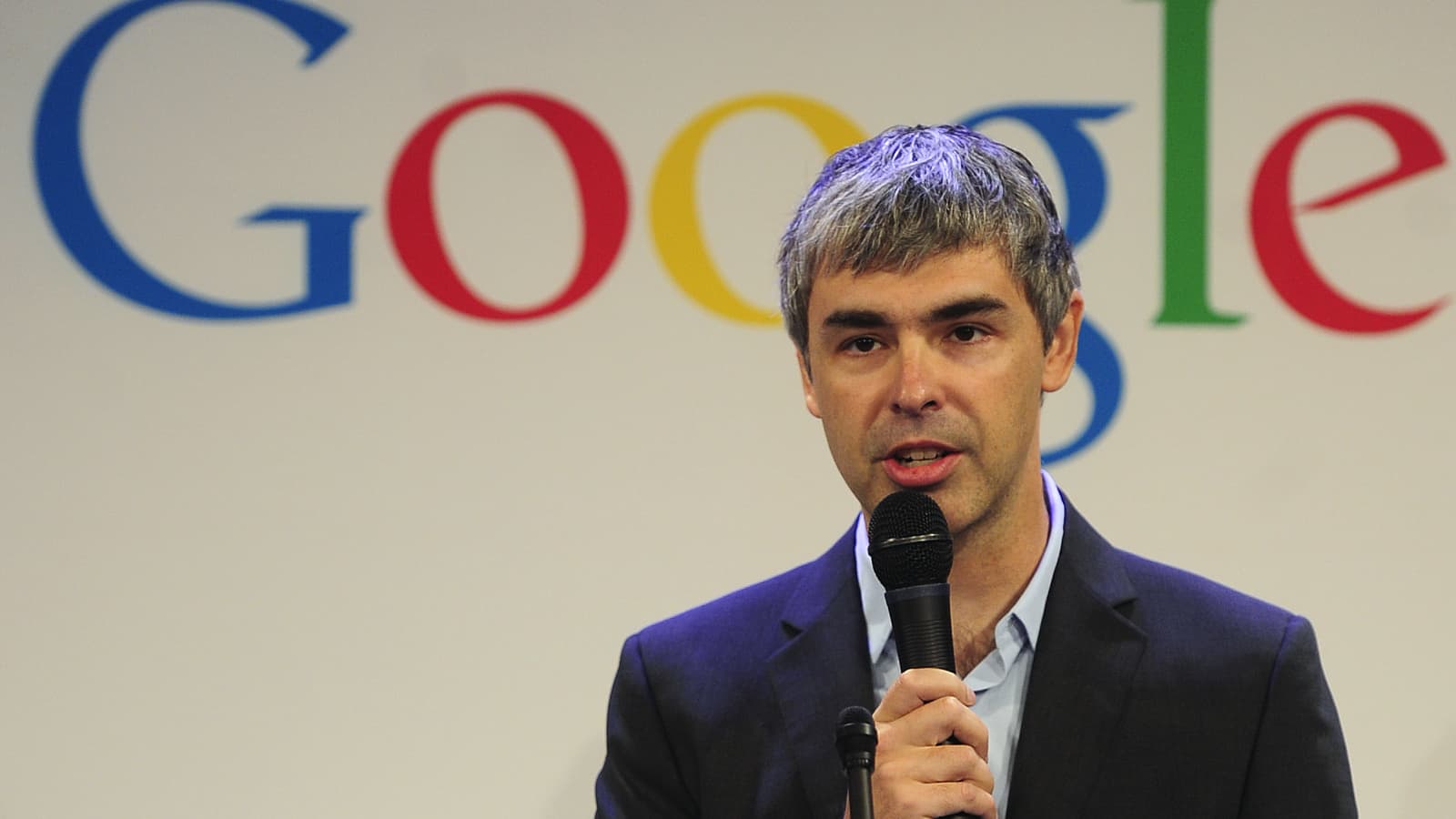 Larry Page wearing a black suit with Google logo on the back
