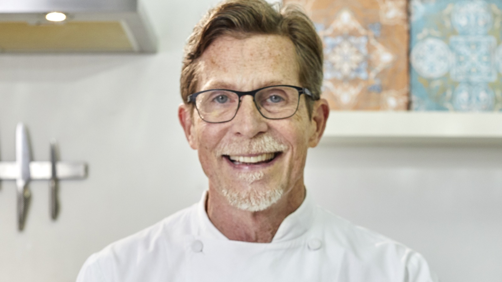 Smiling Rick Bayless wearing a white chef uniform