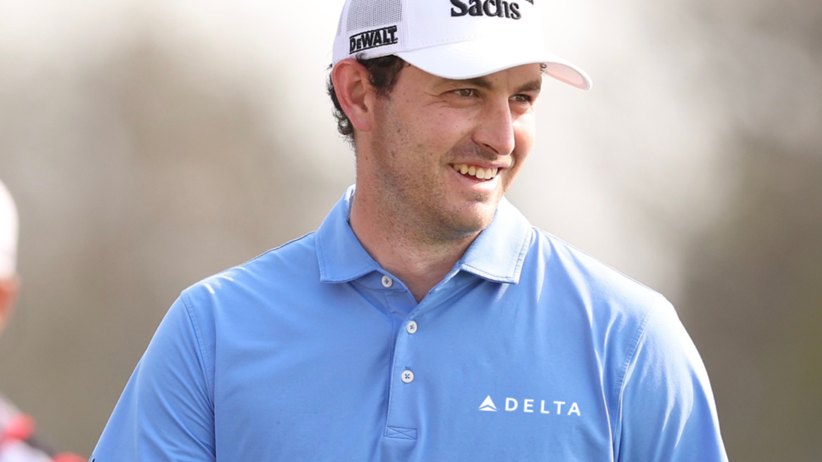 Patrick Cantlay wearing a blue polo shirt and white cap