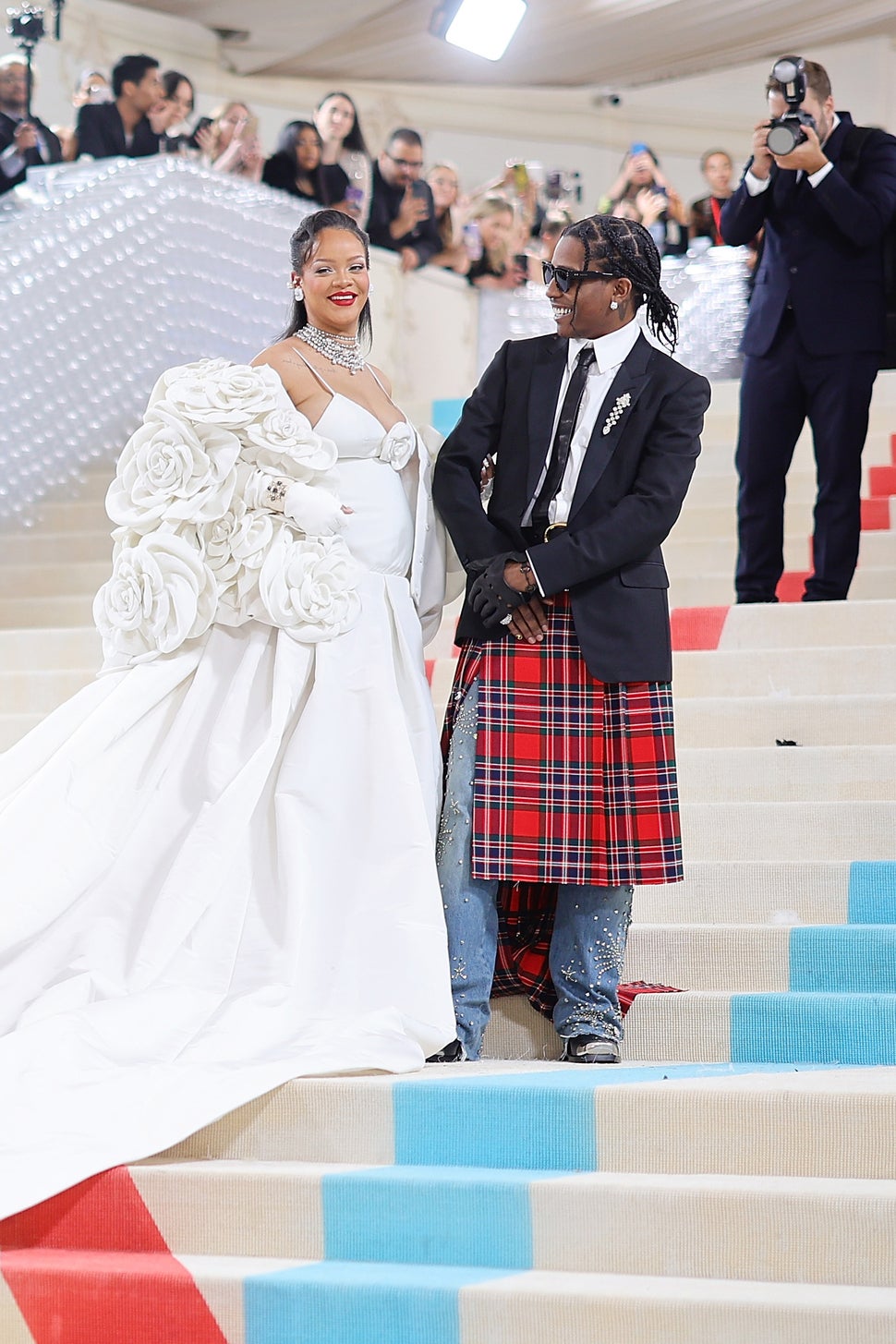 ASAP Rocky wearing suit with red plaid skirt and Rihanna wearing white dress with white floral jacket