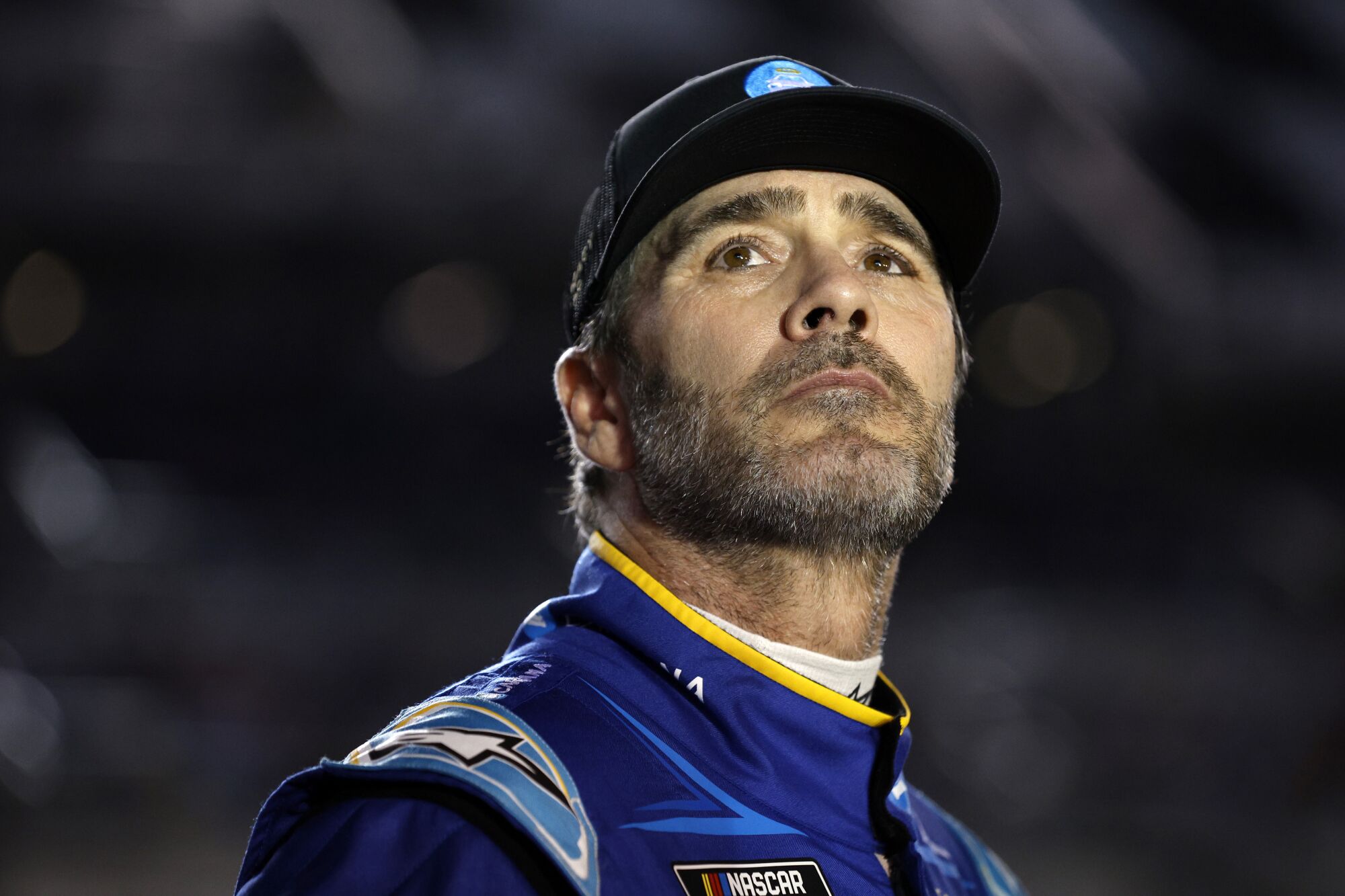 Jimmie Johnson wearing blue racecar outfit and black cap