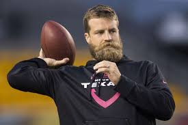 Ryan Fitzpatrick wearing black hoodie jacket while holding a football