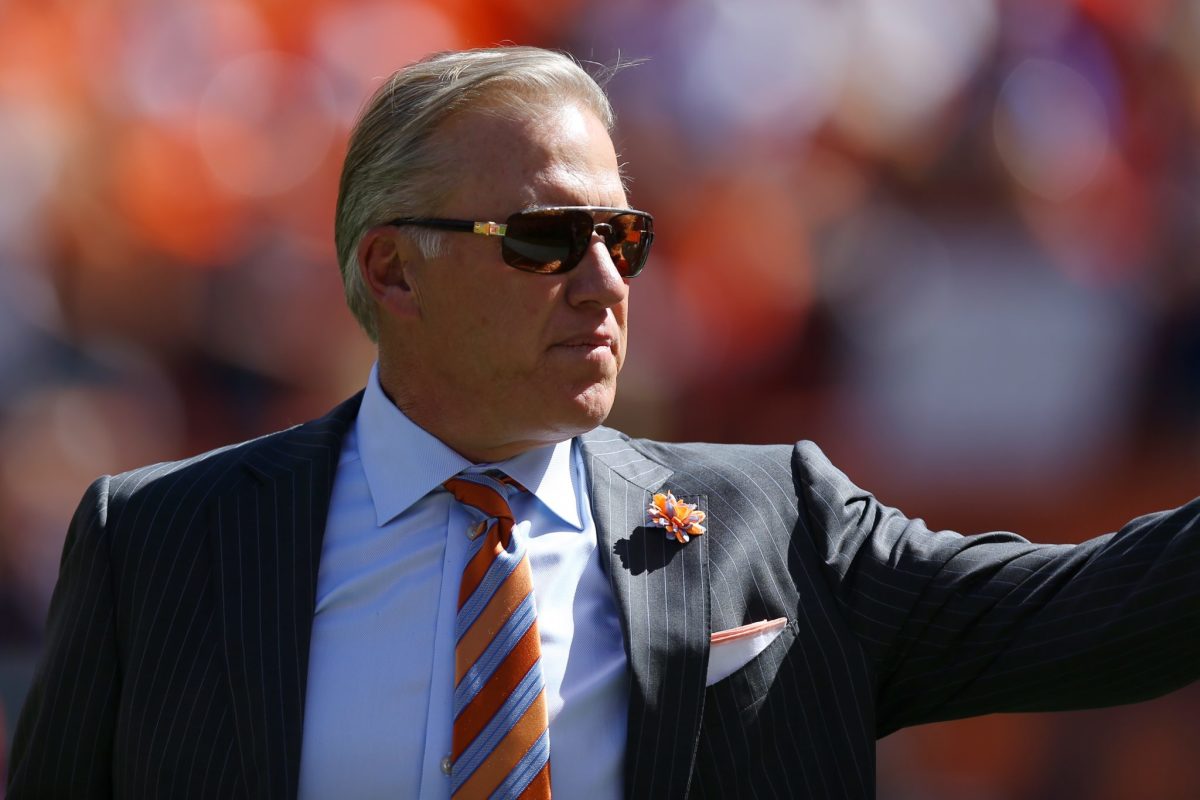 John Elway wearing a black suit and sunglasses