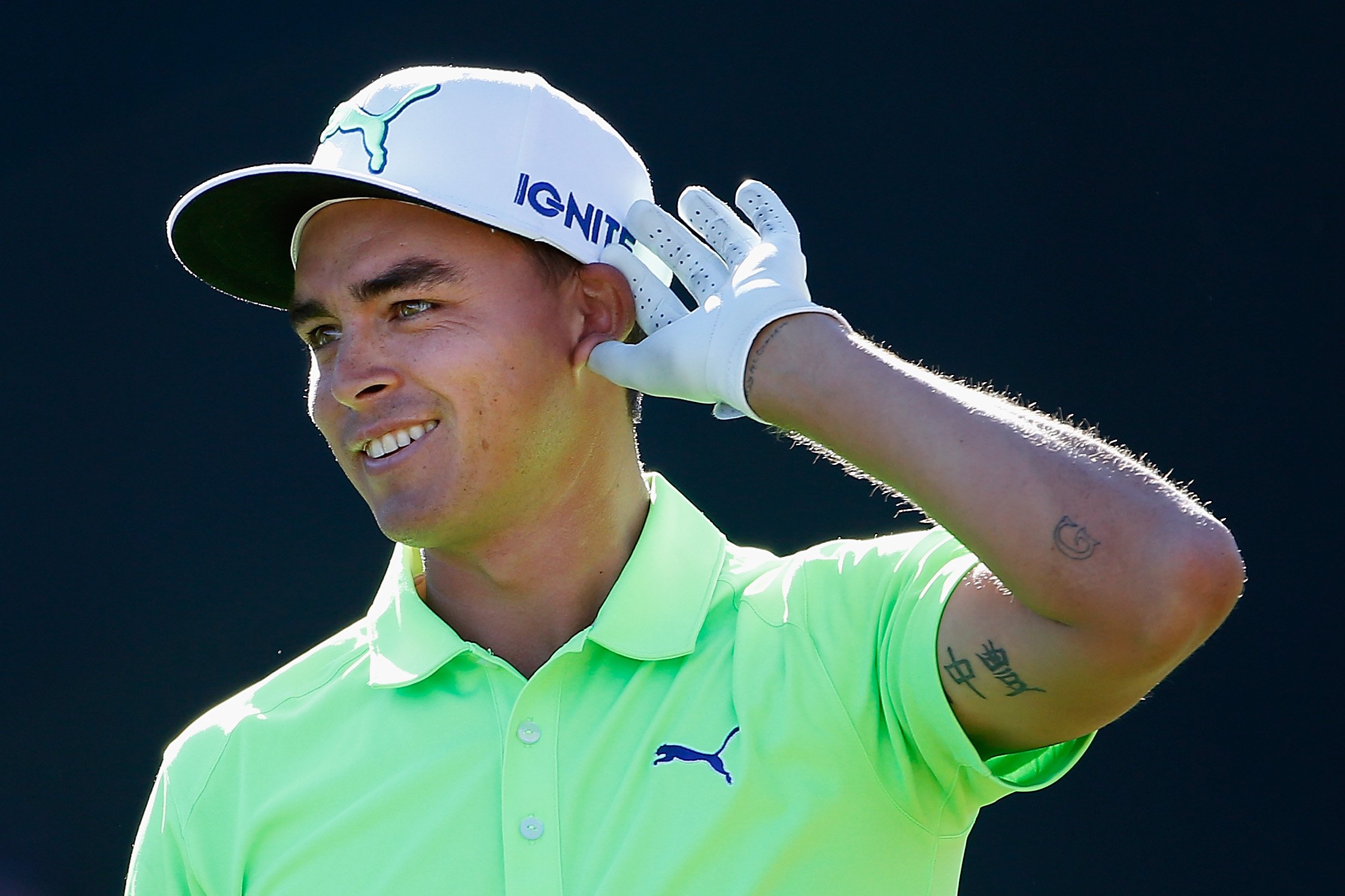 Rickie Fowler wearing green polo shirt and white cap