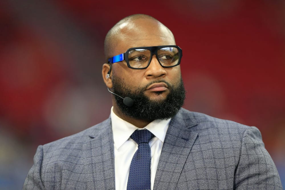 Marcus Spears wearing plaid gray coat and eyeglasses