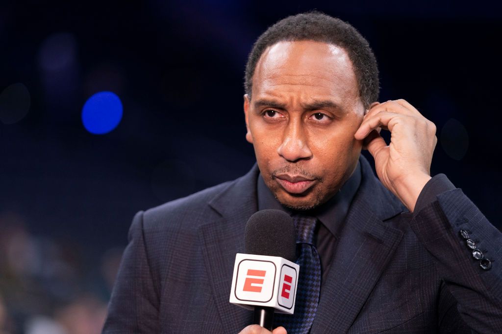 Stephen A. Smith wearing a black suit while holdidng a mic