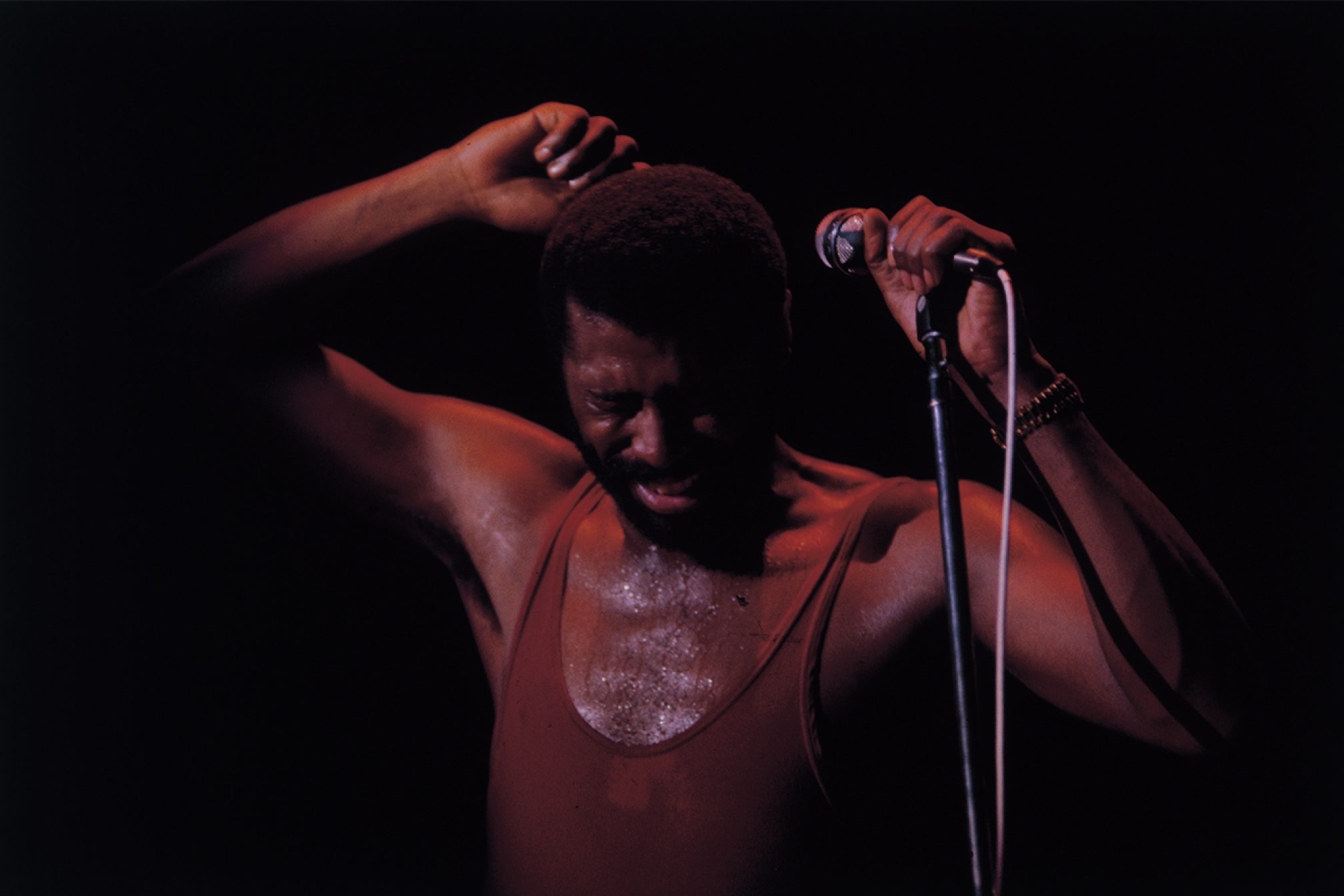 Teddy Pendergrass weearing brown tank top while holding a mic