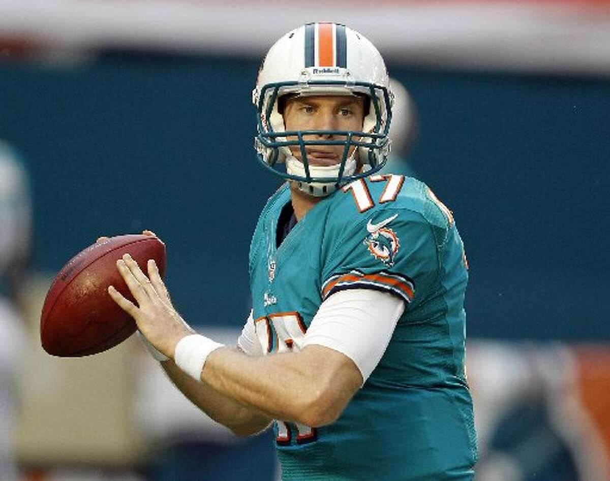 Jordan Cameron wearing a blue green footbal jersey and white helmet while holding a football