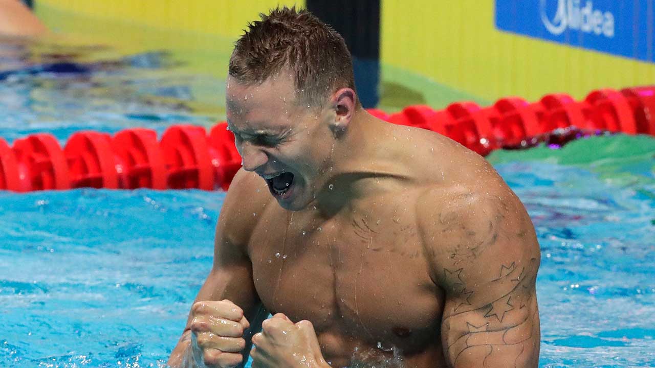Caeleb Dressel celebrating in a swimming pool after winning