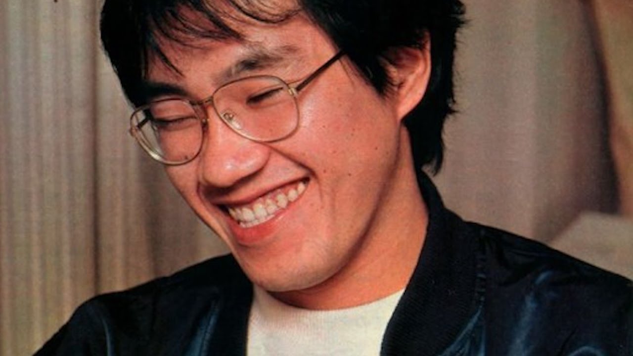 Young Akira Toriyama wearing an eyeglass with a black jacket having a great smile on his face