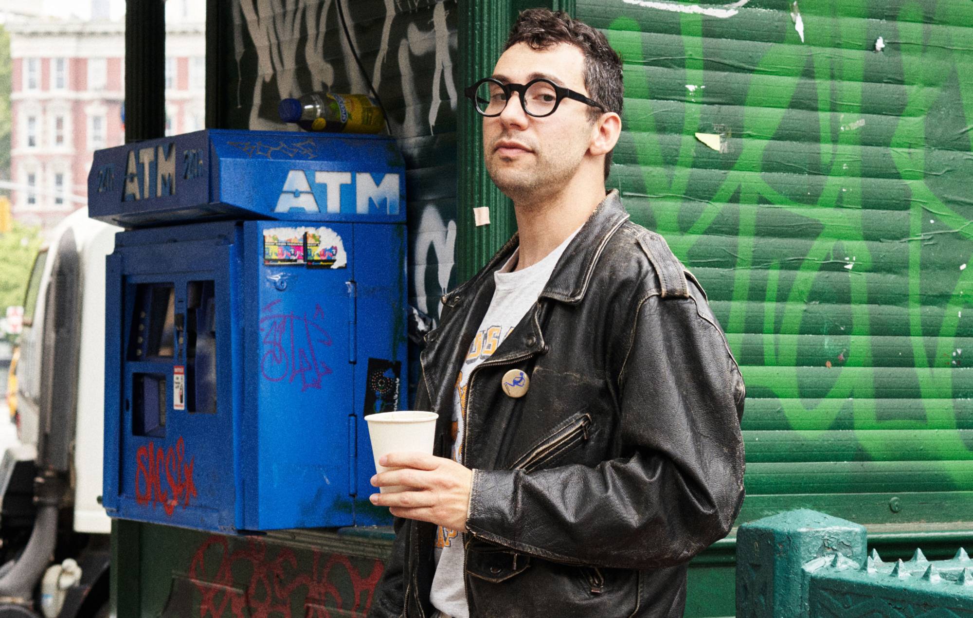 Jack Antonoff wearing a black leather jacket while holding a white paper cup
