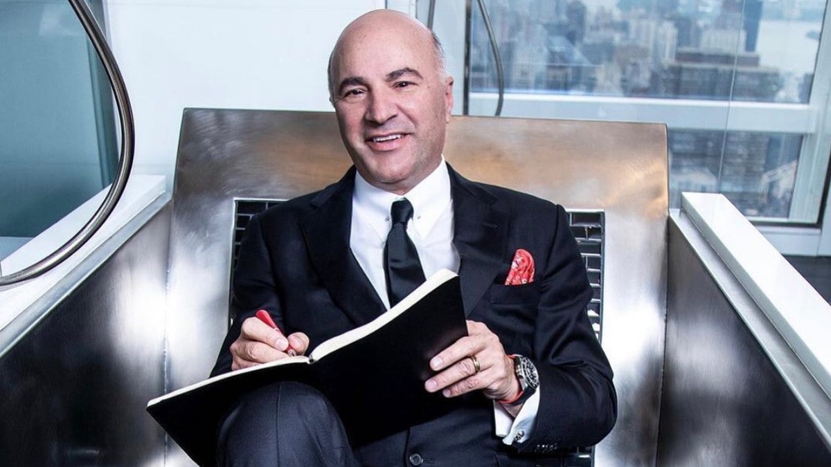 Kevin James O'Leary wearing black suit while holding a book