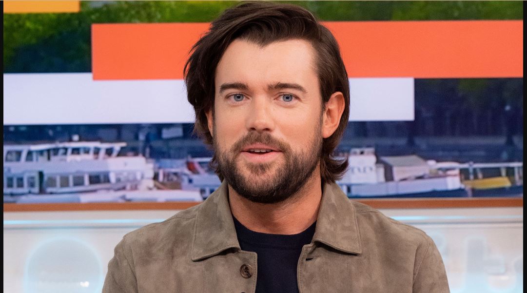 Jack Whitehall wearing a brown jacket on a black t-shirt