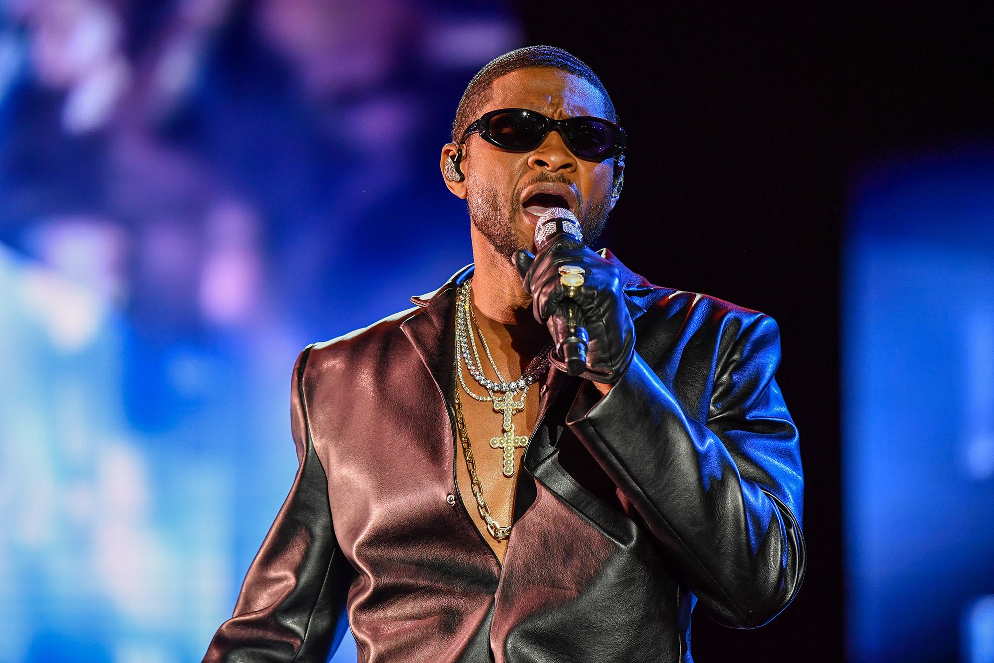 Usher wearing a leather black jacket while holding a mic