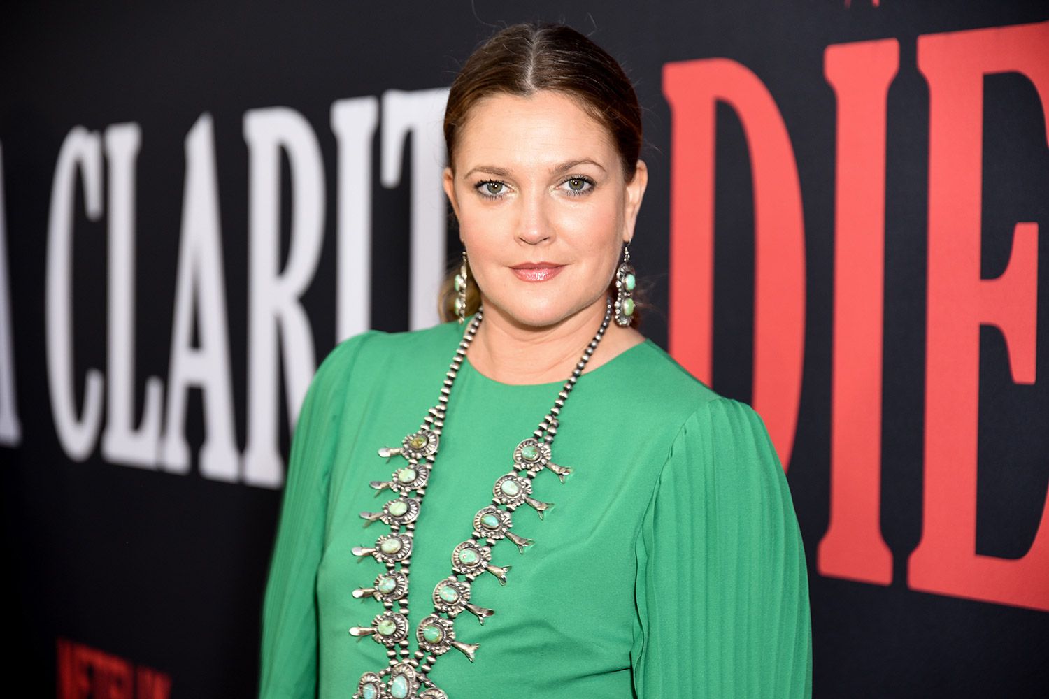 Drew Barrymore wearing a green dress together with big earrings and necklace