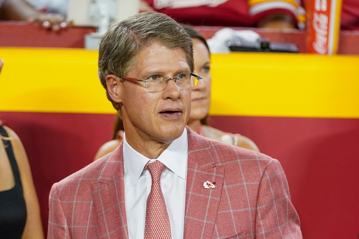 Clark Hunt wearing a plaid red coat and eyeglasses