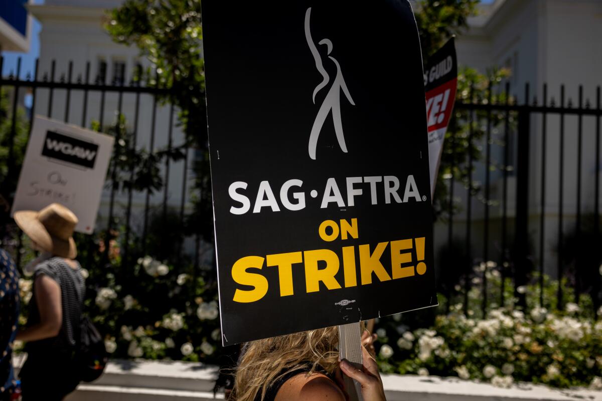 A woman holding a SAG-AFTRA strike poster
