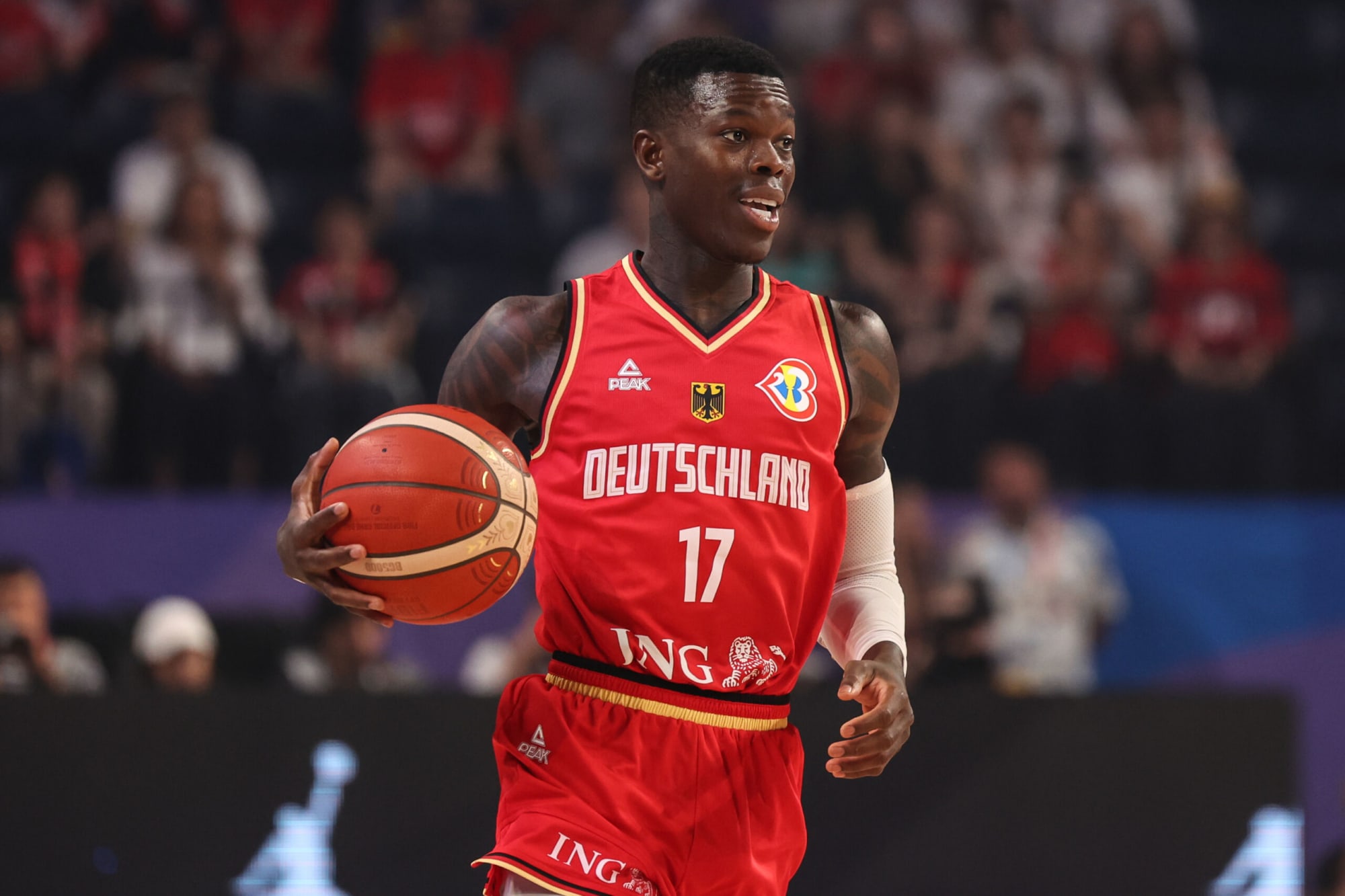 Dennis Schroder wearing a red jersey while holding basketball