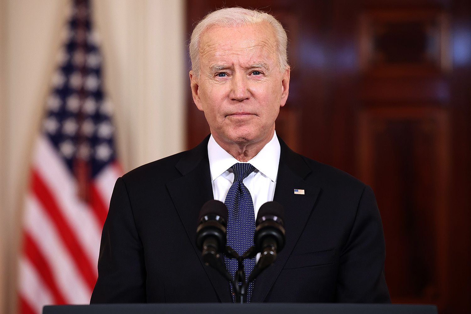 President Joe Biden standing in front of two microphones