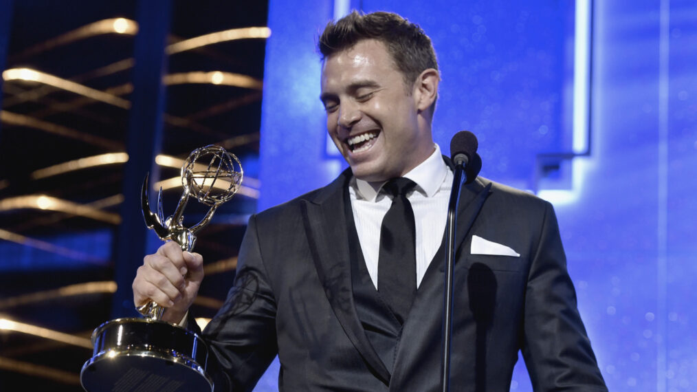Billy Miller wearing a black suit while holding a gold award